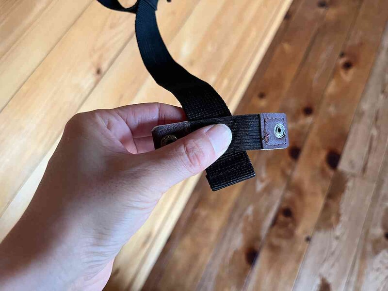 リュックの余ったヒモの端に、キャンドゥの「リュックのヒモ固定バンド BK／BE／BR」を置く