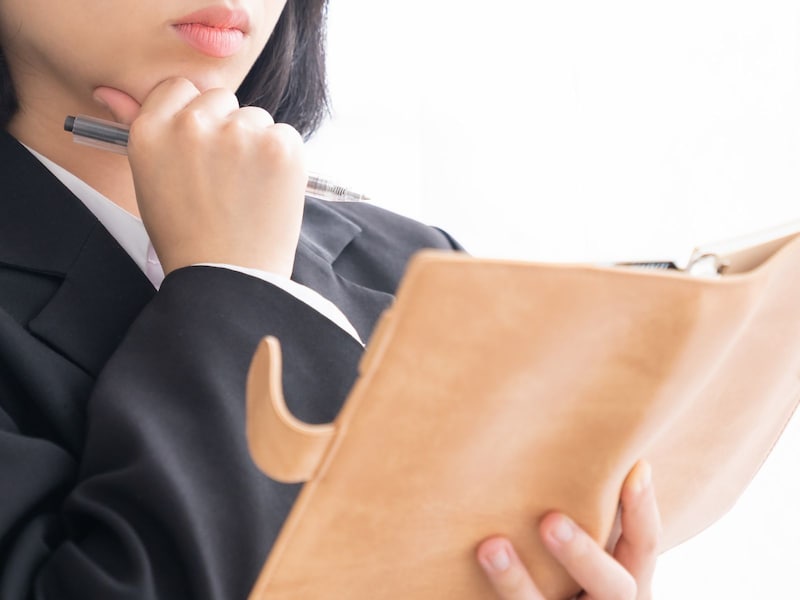 手帳を見て考える女性