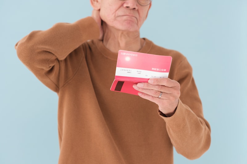 通帳を見て悩む男性