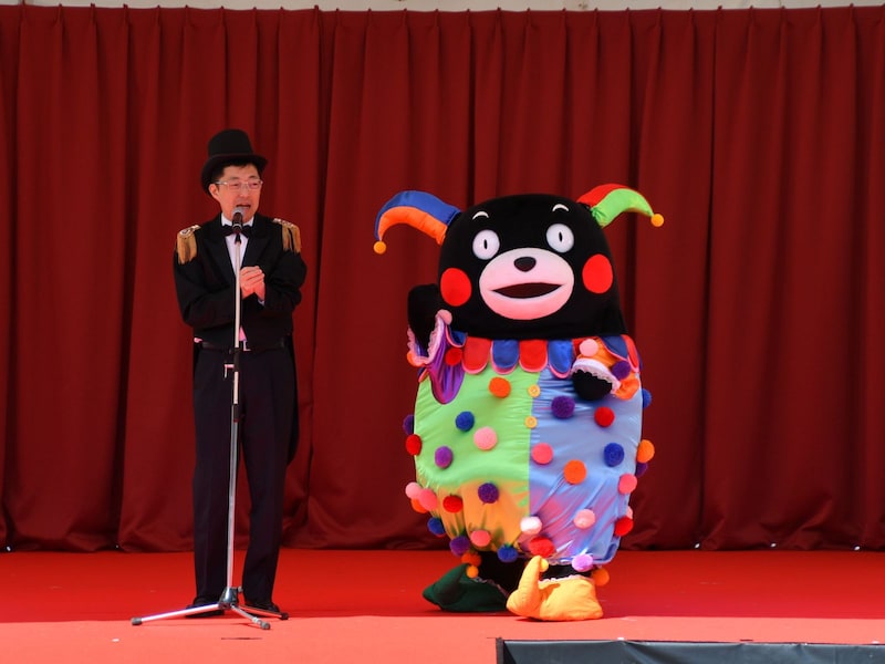 怪しげな手品師風の木村知事（左）と、ピエロのくまモン＝3月14・15日、熊本市