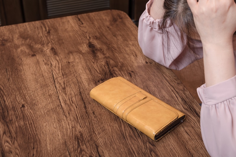 財布を見て頭を抱える女性