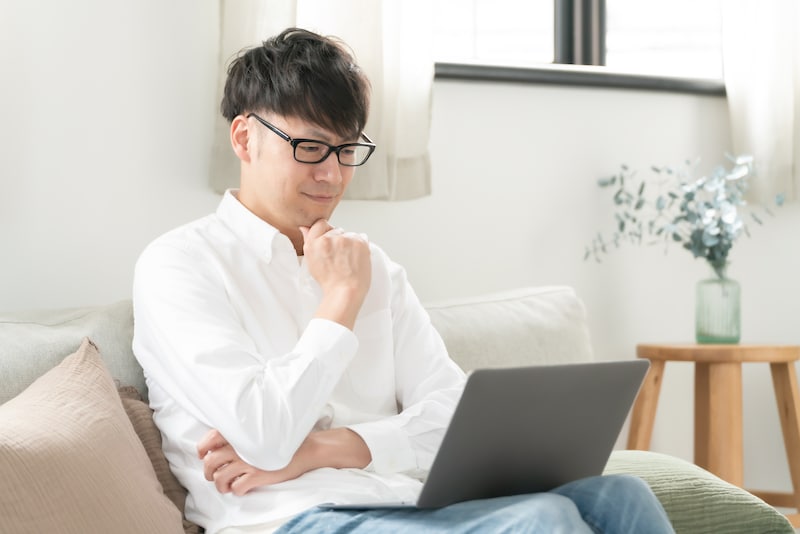 パソコンの画面を見て考える男性