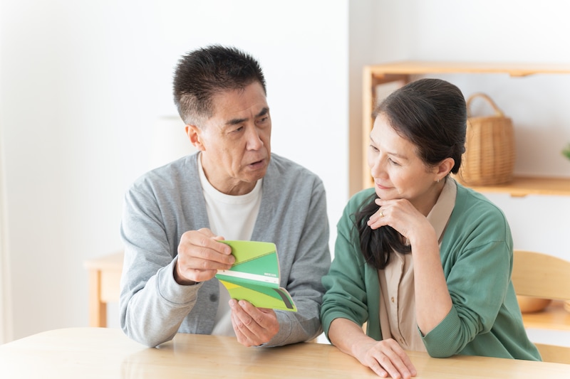通帳を見る夫婦