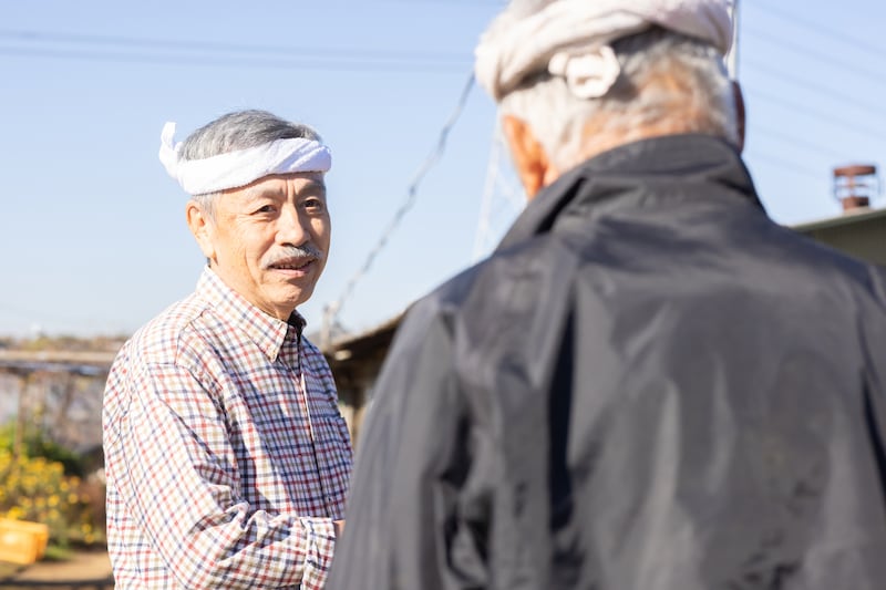 畑で会話をするシニア男性