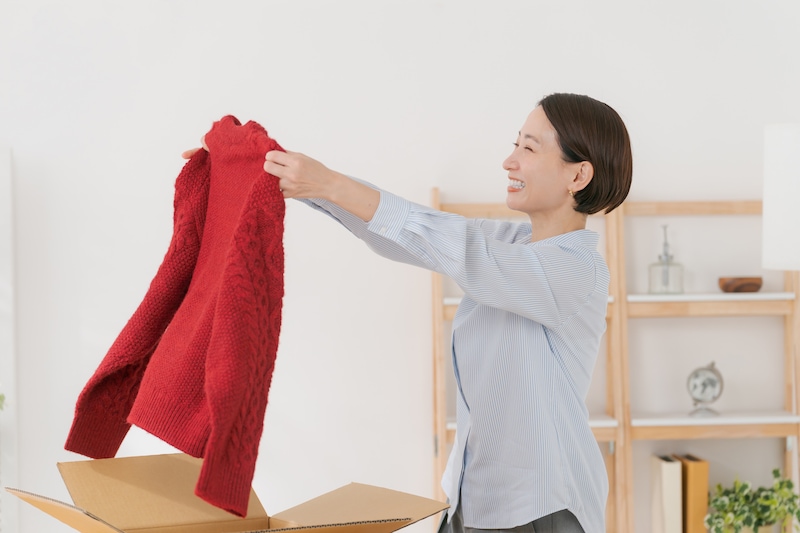 箱からセーターを取り出す女性