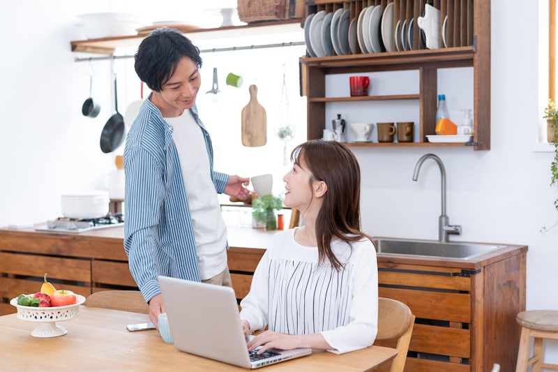 パソコンに向かう妻にコーヒーを淹れる夫