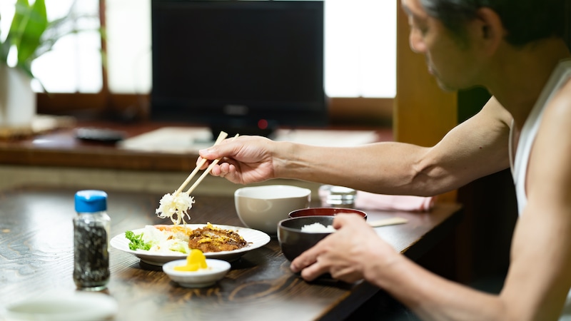 部屋で食事をするシニア男性