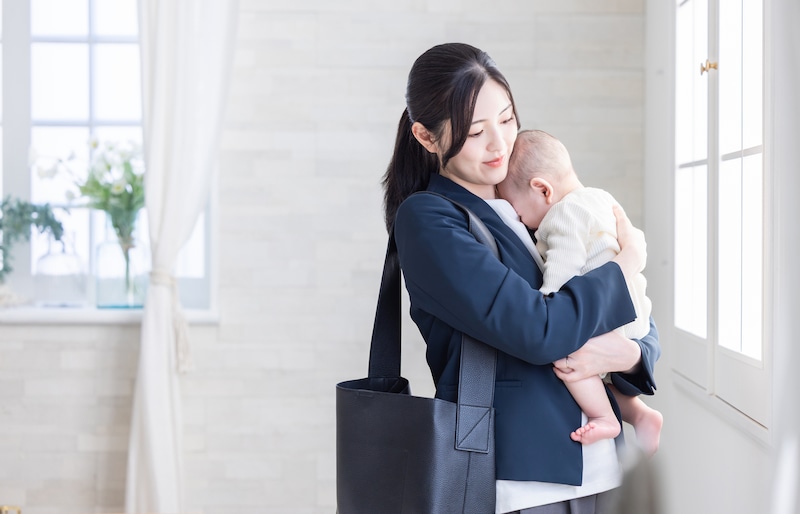 赤ちゃんを抱くスーツ姿の女性