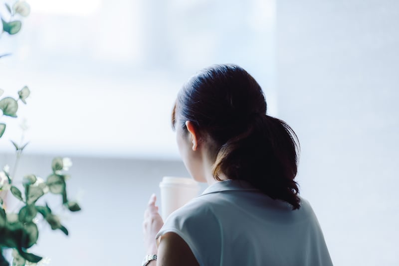 飲み物のカップを持つ女性の後ろ姿