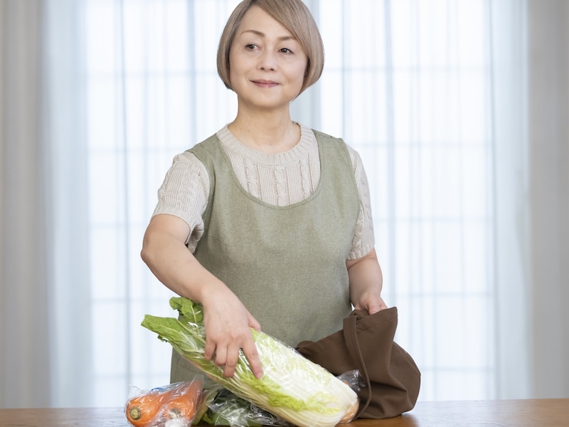 エコバッグから野菜を取り出すシニア女性