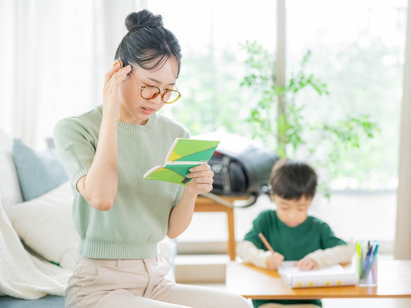 勉強をする男の子と通帳を手に悩む母親