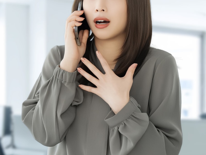 スマホを片手に驚く女性