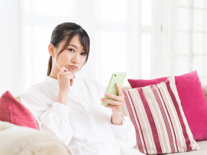 スマホを見て考える女性