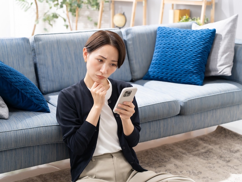 スマホを手に考える女性