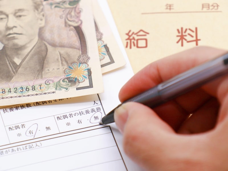 給料袋とお札、履歴書を書く手元