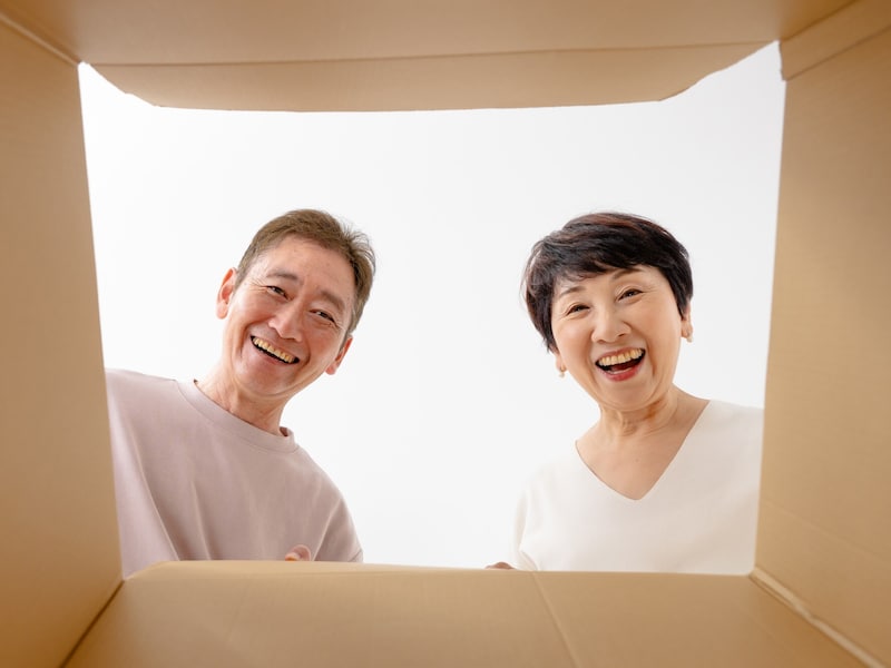 笑顔で段ボールの中を覗き込むシニア夫婦