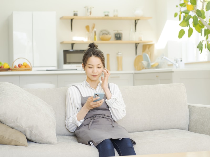 ソファでスマホを手にする女性
