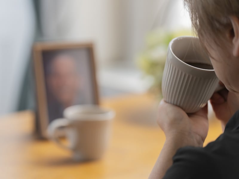 遺影を前にコーヒーを飲む女性