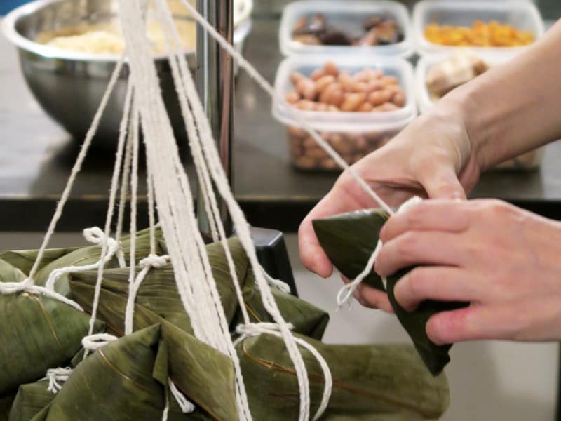 しょう油味のもち米、4種の具材を2枚の笹の葉で包み、三角に折ってひもで結びます。一つひとつ、丁寧に手作りされています（2015年10月9日撮影）