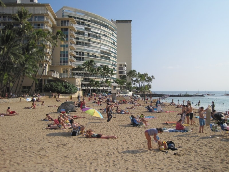 奥の建物がニューオータニ・カイマナ・ビーチ・ホテル。砂浜には木陰はないが、すぐ後ろにヤシの木が並ぶ芝生がある