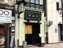 薄いうぐいす色の壁に黒の看板が印象的な同店