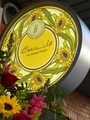「オクシタニアル 東京本店」の看板にはセミのマークとヒマワリの花の柄が