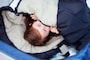 寝袋で眠る子供