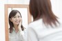 鏡を見て微笑む女性