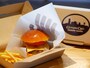 大正12年創業「尾島商店」の人気ハンバーガーをアレンジした「GUNDAM FACTORY YOKOHAMA チーズバーガー Produced by 尾島商店（1430円）」。RX78-F00ガンダムのハンドがプリントされた包み紙で提供（2020年11月30日撮影）