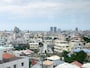 那覇の住宅街らしい風景。コンクリートの建物がぎゅうぎゅうにひしめき合う先に青い海が見える