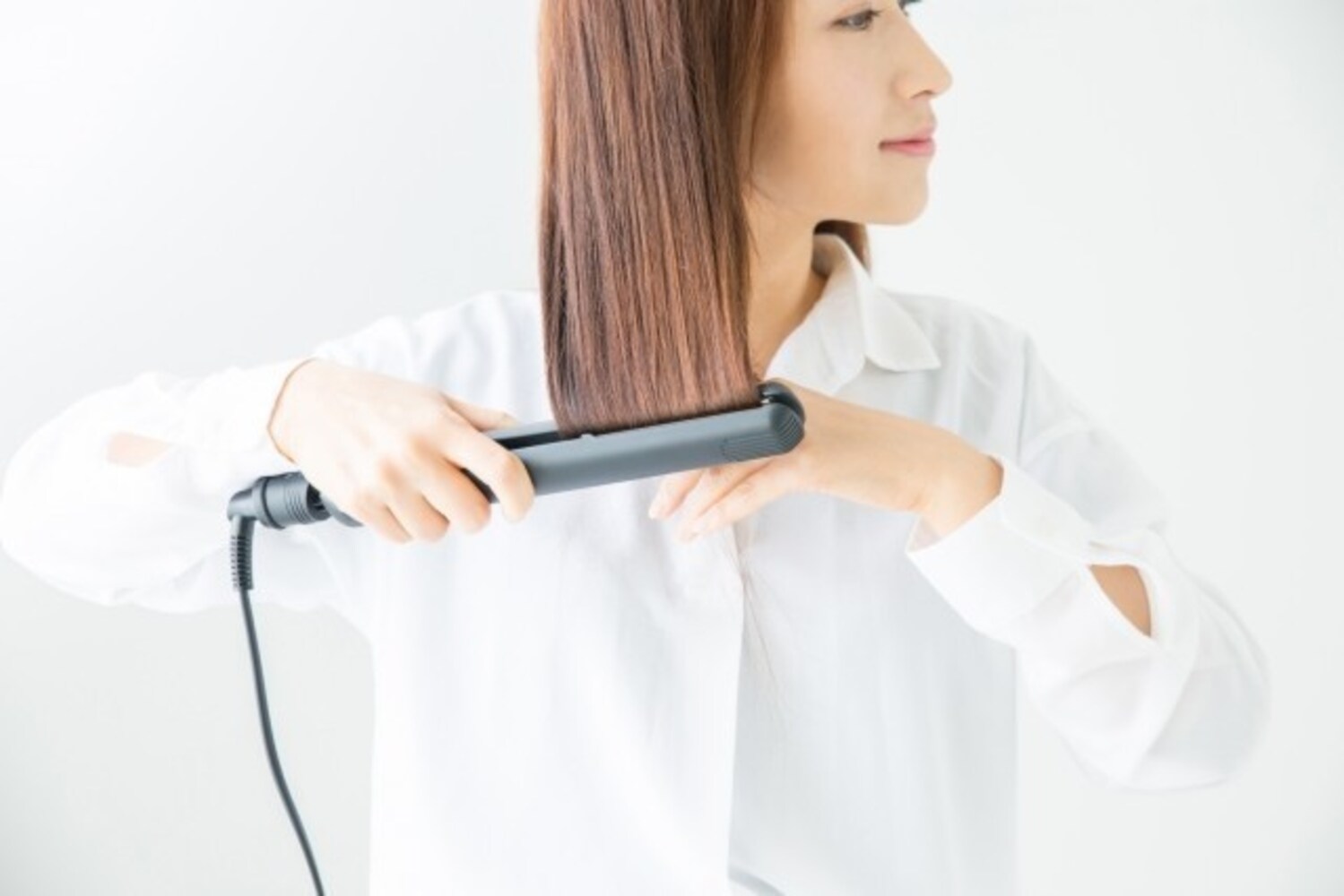 2.真下に引っ張るように耳下の毛束にアイロンをあてる