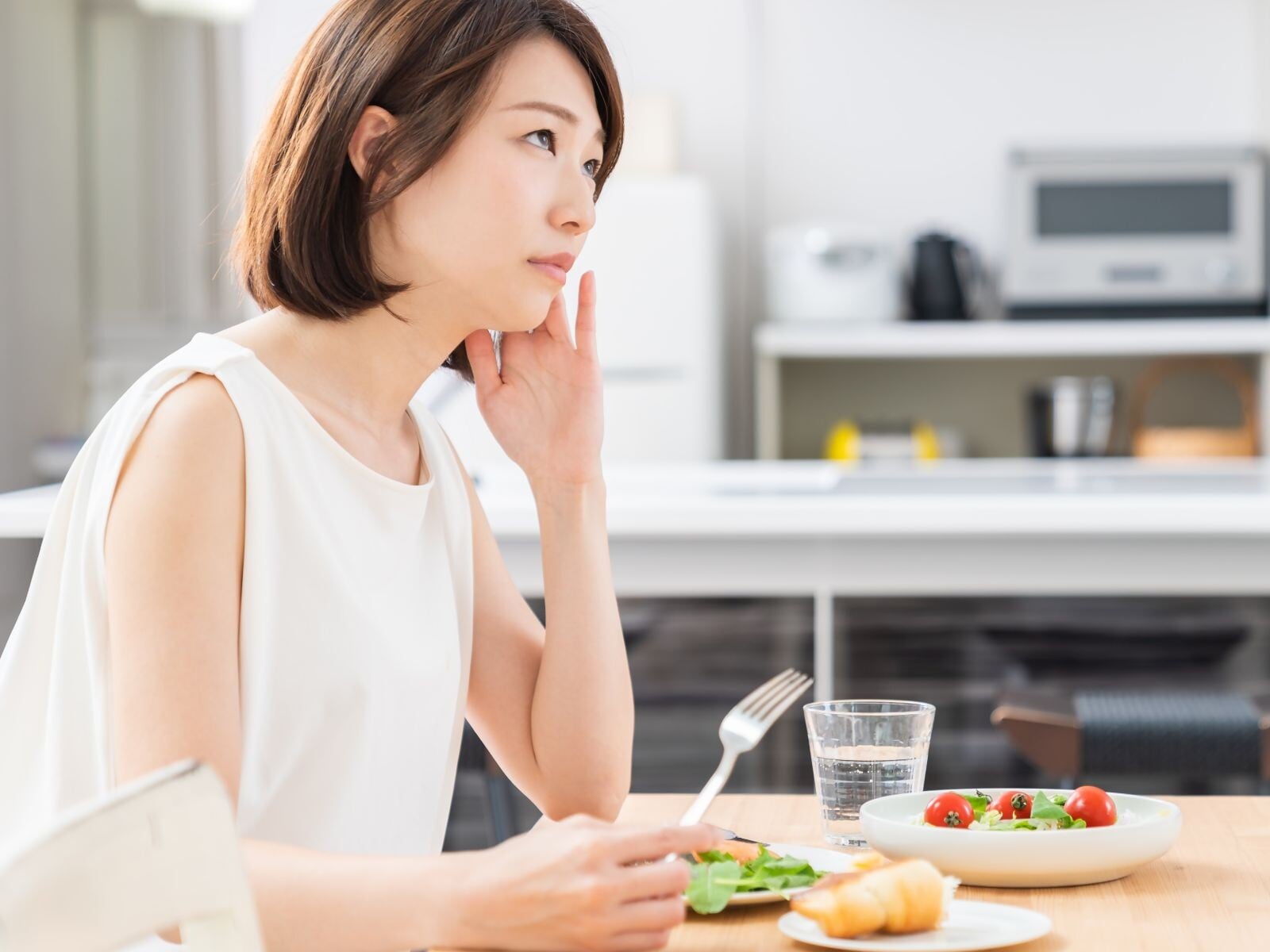 朝食を食べながら悩む女性