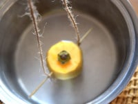 たっぷりのお湯を鍋に沸かしたら、紐の部分を持ち、柿を熱湯に浸けて、表面を10秒ほど煮沸消毒します。