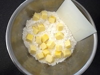 ホットケーキミックスをボウルに入れ、角切りにしたバターを加え、カード（なければナイフ)でバターを粉にまぶしながら、切り刻みます。