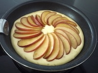 フライパンにホットケーキミックスを流し入れ、上にりんごを並べます。蓋をして、弱火で15分、パンケーキの表面まで火が通ったらできあがりです。