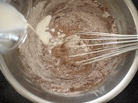 ホットケーキミックスとカカオパウダーを合わせてふるい、牛乳と交互に2回に分けて加え、粉っぽさがなくなるまで混ぜます。生地をカップケーキの型に入れます。