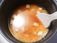 内釜に米を移し、調味料を加え、2合の線まで水を足し、餅を加えてヘラで混ぜる。