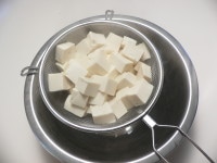 鍋に湯を沸かし、1cm角に切った豆腐を入れ、ゆらゆらと浮かんできたらザルに上げ、水気を切る。<br />
<br />
ほうれん草はサッと茹でて水に取り、水気を絞って4～5cmに切る。エリンギはイチョウ切りにする。チーズは5～6mm角に、ハムは1cm角に切る。