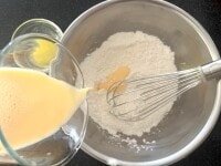 計量カップに牛乳と卵を入れ、全体をよく混ぜ、粉類に少しずつ加え、泡立て器で混ぜます。