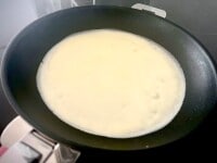 フライパンにサラダ油、またはバターをひき、中火で熱します。レードル（お玉）1杯の生地をフライパンに流し入れ、回して丸い形にします。