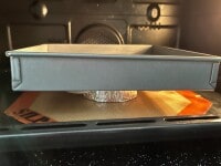 クロワッサンロールの上にオーブンペーパーをのせ、底が平らなケーキ型（写真はスクエア型）を上部が膨らまないように重しとしてのせ、予熱しておいた220度のオーブンで20分焼きます。