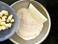 1cm角に切ったバターを粉類に加え、バターが米粒大になるまで、粉をまぶしながら、カードでバターを切り刻みます。