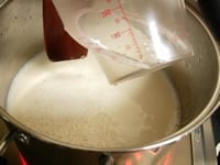 鍋（B）の豆乳を中火にかけ、かき混ぜながら75～80度にします。「にがり」（ぬるま湯80mlに、にがり水大さじ1）をしゃもじに伝わらせ少しずつ加えます。しゃもじでゆっくりと十文字を切り、蓋をして10分ほどおいておきます。
