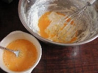 ボールにバターを入れて泡立て器でクリーム状になるまで混ぜ、三温糖を加えて白っぽくなるまでよくすり混ぜます。次に溶いた卵を数回に分けて少しずつ加え、分離しないようその都度よく混ぜ合わせます。<br />