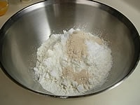 強力粉と薄力粉を合わせて振るいます。ボウルに、振るった粉類、砂糖、塩、ドライイーストを入れ、木べらや泡立て器を使って良く混ぜ合わせます。