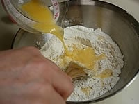 卵と合わせたぬるま湯(40℃)を粉の中央に少しずつ加え、木べらを使いまわりの粉と混ぜ合わせます。※1割ほどを残して、その日の湿度に合わせて微調整すると尚良いです
