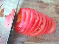 トマトをよく洗い、水気をふき取ってから5mm幅の輪切りにします。（※ガイドのワンポイントアドバイス参照）<br />
<br />
輪切りにしたトマトをお皿に盛り付けます。<br />