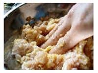 鶏つくねの種を作ります。ねぎはみじん切りにし、生姜は皮をむいておろします。卵を溶いて酒、塩、こしょうを加えたものにパン粉を浸け、パン粉が湿ってやわらかくなったら鶏肉に加えます。生姜とねぎも加え、粘り気が出るまで練ります。<br />