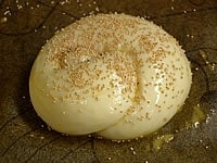 生地を細長くひも状に伸ばし、軽く結んだ形のバターロールも作ってみました。照り用の卵水（卵1個を水大さじ1で溶いたもの）を塗ったあと、けしの実（黒ごまも美味しい）を振りかけます。 オーブンは200℃に余熱しておきます。
