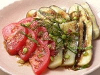 ナスを皿に並べ、トマトを盛りつけ、刻んだ小葱とせん切りにした大葉を散らし、 ゴマソースをかける。  　
